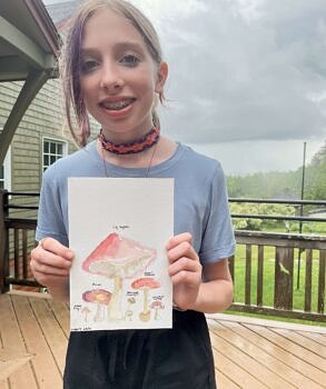 A summer camper holds her mushroom watercolor. (photo © Audrey Dunn)