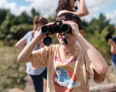 A young student peers through binoculars. (photo © Ben Conant)