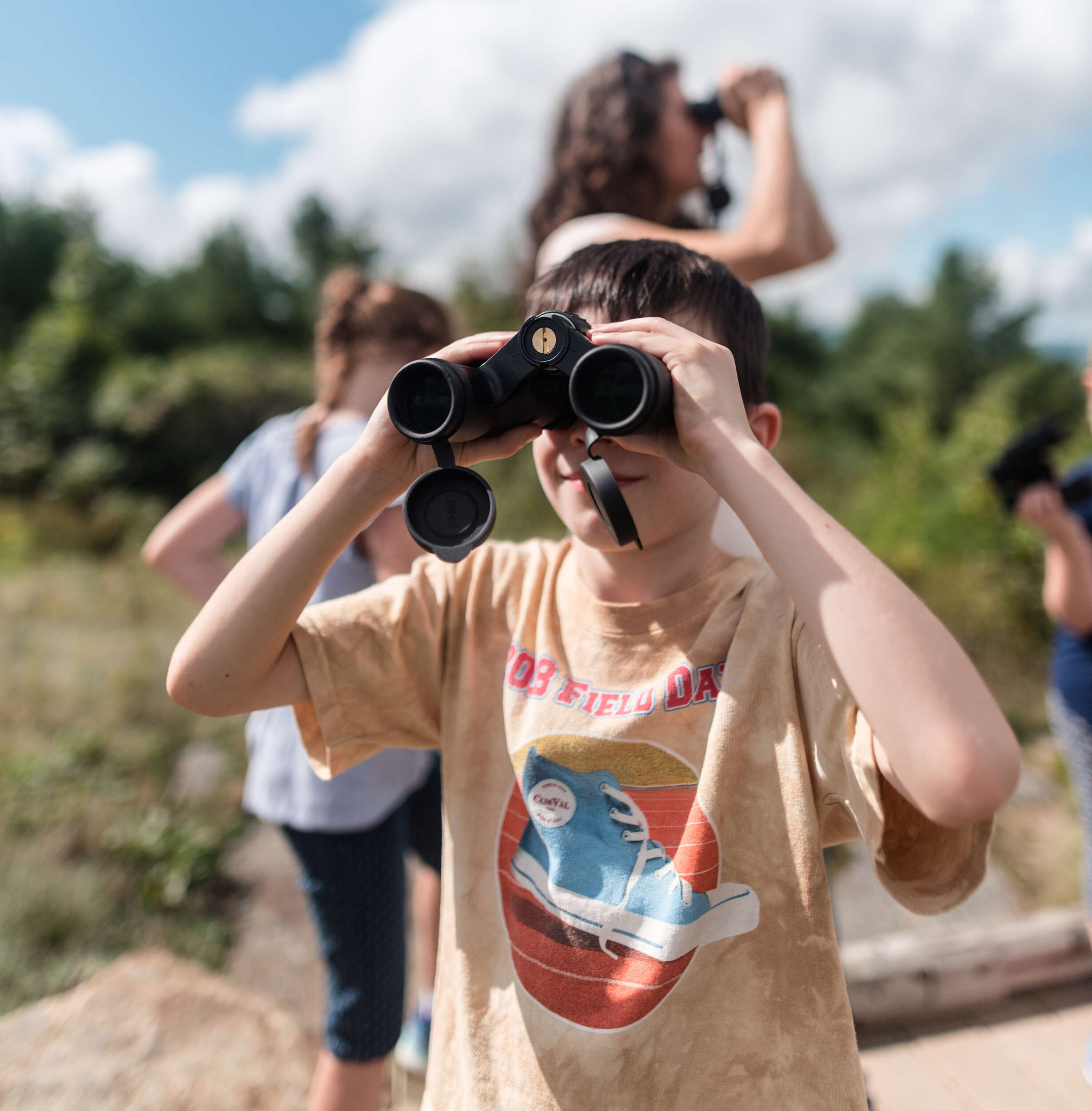 A young student peers through binoculars. (photo © Ben Conant)