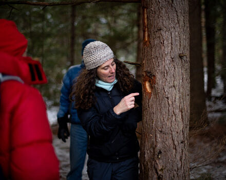 Susie points at a woodpecker hole in a tree trunk. (photo © Ben Conant)