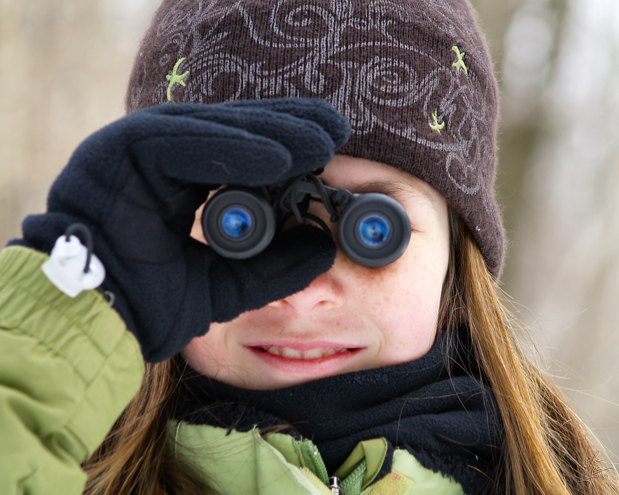 A girl, dressed for winter, looks through binoculars. (photo © Eric Begin)