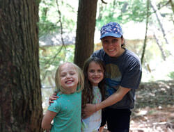 Hannah Blair and two girls smile in the forest.