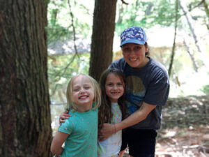 Hannah Blair and two girls smile in the forest.