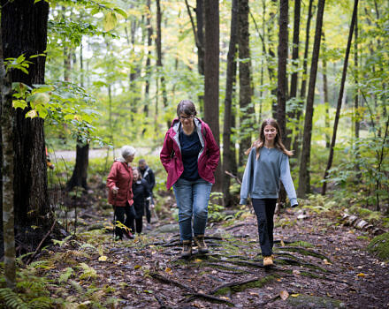 A mother and daughter hike through the woods, with other hikers visible in the distances. (photo © Ben Conant)