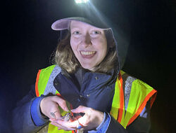 Chloe March smiles while holding a spotted salamander.
