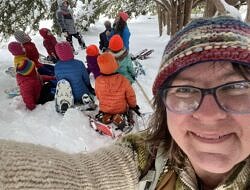 Karen Rent takes a winter selfie with a group of students in the background.