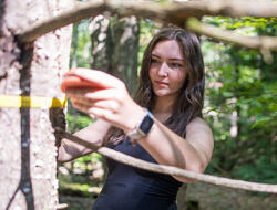 Lexi Barrett uses a DBH tape to measure the diameter of a tree.
