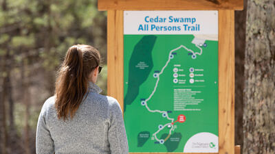 A woman looking at a trail map (Photo © Rooted in Light Media)