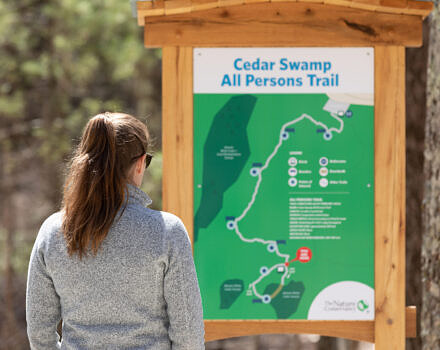 A woman looking at a trail map (Photo © Rooted in Light Media)