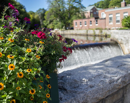 An old brick building with flowers and waterfall in the foreground (Photo by Linda Dee)