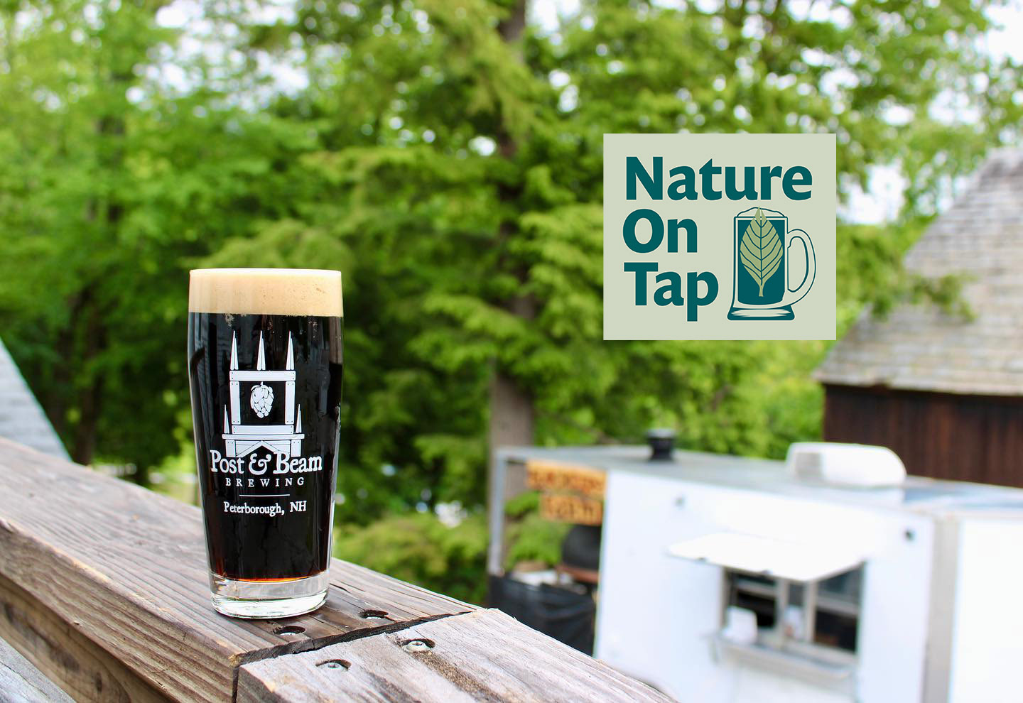 A dark beer in a pint glass sitting on a porch railing (Photo © Post & Beam Brewing)