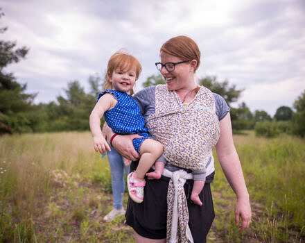 Mother holding her daughter and baby in a field