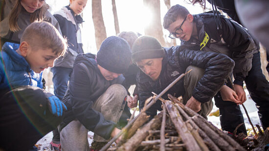 Kids and man building a fire in the woods (Photo © Ben Conant)