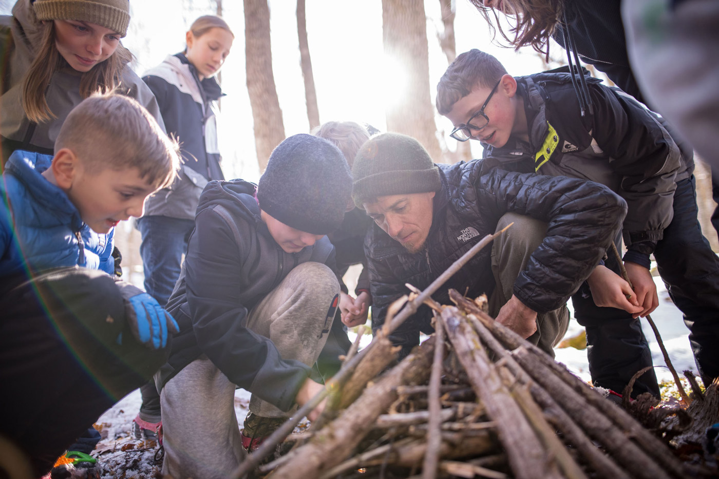 Kids and man building a fire in the woods (Photo © Ben Conant)