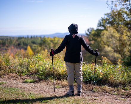 A hiker looks out into the distance with their arms outstretched. (photo © Ben Conant)